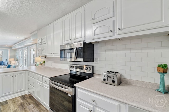 1406 Jones Ave, Tybee Island, GA 31328 - kitchen featuring appliances with stainless steel finishes, a textured ceiling, white cabinetry, light countertops, and wood finished floors