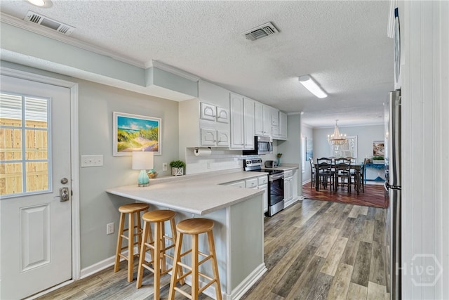 1406 Jones Ave, Tybee Island, GA 31328 - kitchen with appliances with stainless steel finishes, a kitchen bar, a textured ceiling, light wood finished floors, and light countertops