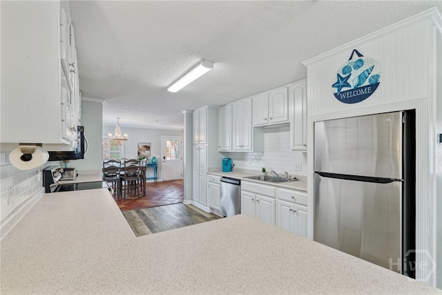 1406 Jones Ave, Tybee Island, GA 31328 - kitchen with stainless steel appliances, a sink, a chandelier, dark wood-type flooring, and light countertops