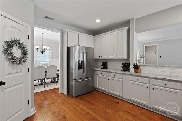 115 Meadowlands Dr, Rincon, GA 31326 - kitchen with stainless steel fridge with ice dispenser, a chandelier, wood finished floors, decorative backsplash, and white cabinets