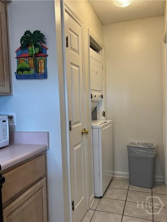 1 Center St Unit 3, Tybee Island, GA 31328 - washroom with stacked washing machine and dryer, light tile patterned flooring, a textured ceiling, and baseboards