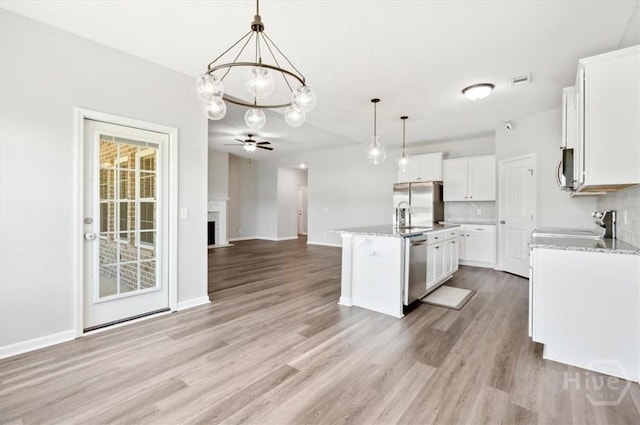 301 Akins Ranch Rd NE, Ludowici, GA 31316 - kitchen with appliances with stainless steel finishes, light wood-style flooring, open floor plan, a kitchen island with sink, and hanging light fixtures