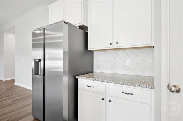 301 Akins Ranch Rd NE, Ludowici, GA 31316 - kitchen with stainless steel fridge, wood finished floors, tasteful backsplash, white cabinets, and baseboards