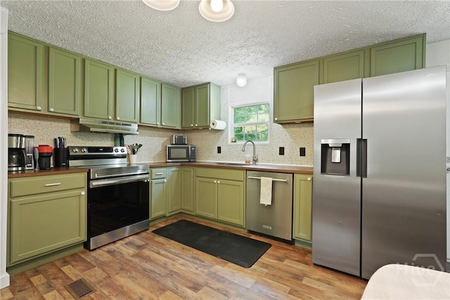132 Waymaker Dr, Midway, GA 31320 - kitchen with green cabinetry, stainless steel appliances, under cabinet range hood, a textured ceiling, and light wood-type flooring