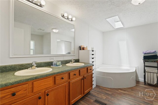 132 Waymaker Dr, Midway, GA 31320 - bathroom with a skylight, double vanity, a garden tub, wood finished floors, and a textured ceiling