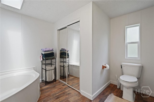 132 Waymaker Dr, Midway, GA 31320 - full bathroom with a bath, wood finished floors, a textured ceiling, toilet, and baseboards