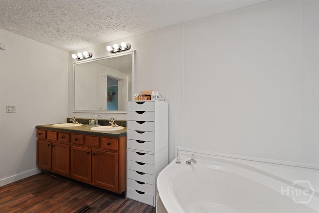 132 Waymaker Dr, Midway, GA 31320 - full bathroom featuring wood finished floors, double vanity, a bath, and a textured ceiling