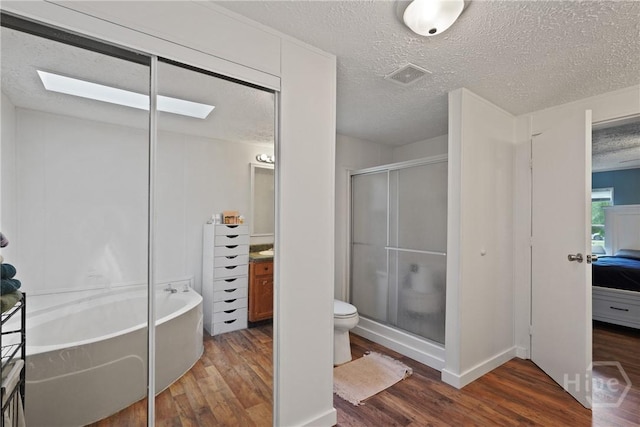 132 Waymaker Dr, Midway, GA 31320 - bathroom featuring wood finished floors, a stall shower, a garden tub, toilet, and a textured ceiling