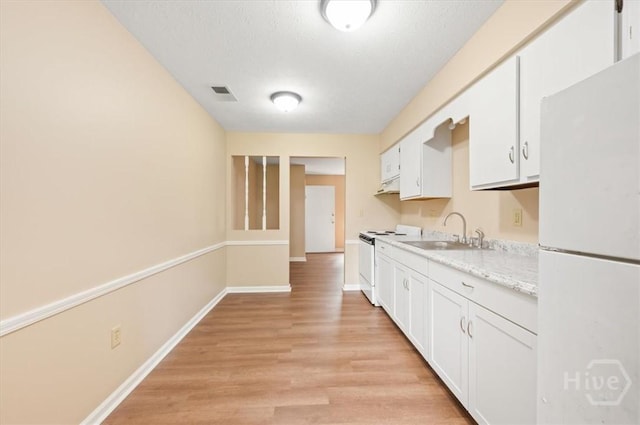 310 Ashmore St Unit A, B, Hinesville, GA 31313 - kitchen with white appliances, a sink, light wood finished floors, white cabinetry, and baseboards