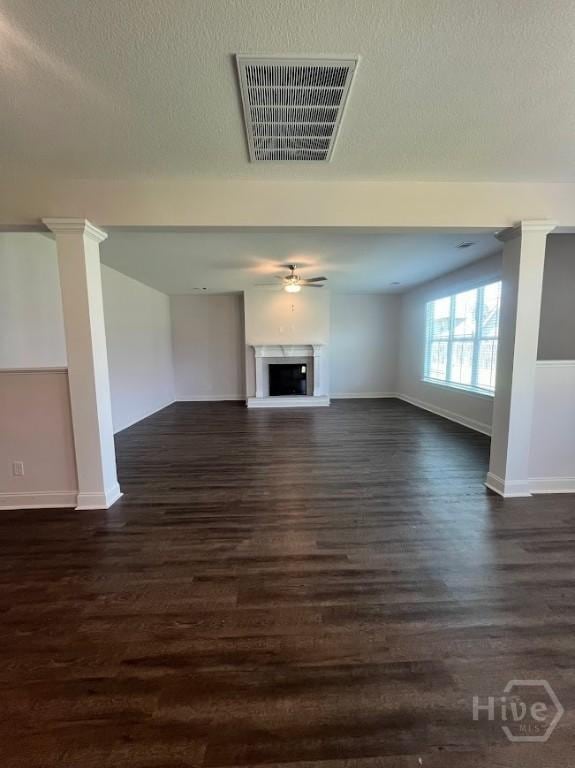 139 Sams Dr, Guyton, GA 31312 - unfurnished living room with baseboards, dark wood-style flooring, a fireplace with raised hearth, and ceiling fan