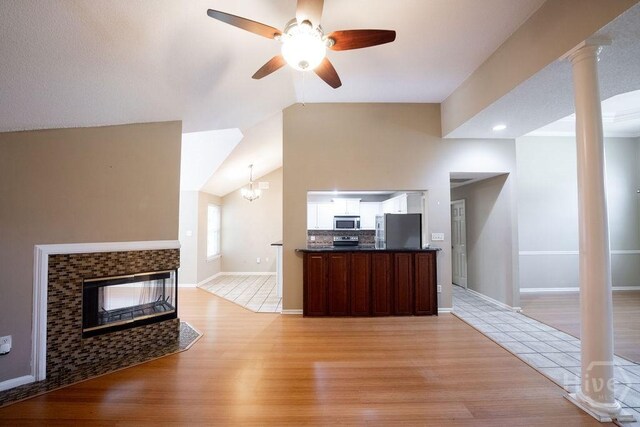 143 Village Lake Dr, Pooler, GA 31322 - unfurnished living room featuring light wood finished floors, vaulted ceiling, ceiling fan, baseboards, and a tiled fireplace