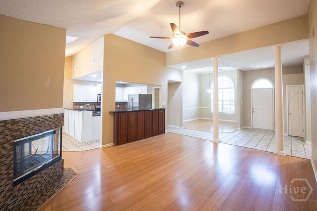 143 Village Lake Dr, Pooler, GA 31322 - unfurnished living room featuring ornate columns, light wood-style floors, ceiling fan, a brick fireplace, and vaulted ceiling