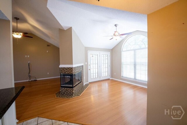 143 Village Lake Dr, Pooler, GA 31322 - unfurnished living room with ceiling fan, vaulted ceiling, a tiled fireplace, light wood-type flooring, and baseboards