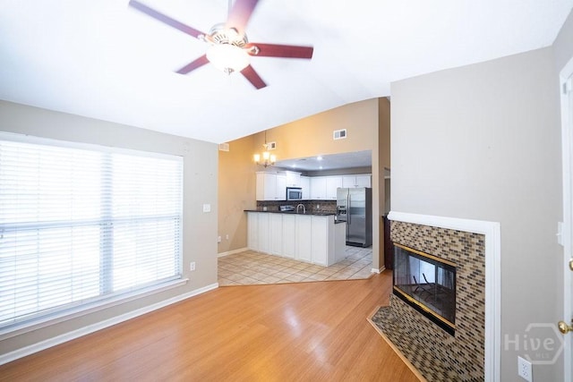 143 Village Lake Dr, Pooler, GA 31322 - unfurnished living room featuring a ceiling fan, light wood-style floors, lofted ceiling, a tile fireplace, and baseboards