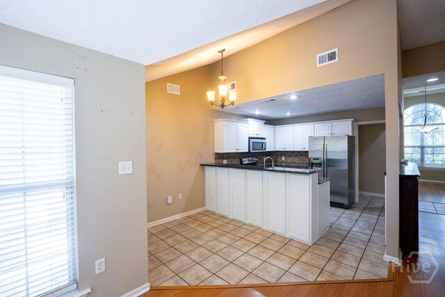 143 Village Lake Dr, Pooler, GA 31322 - kitchen featuring stainless steel appliances, dark countertops, a peninsula, a chandelier, and backsplash