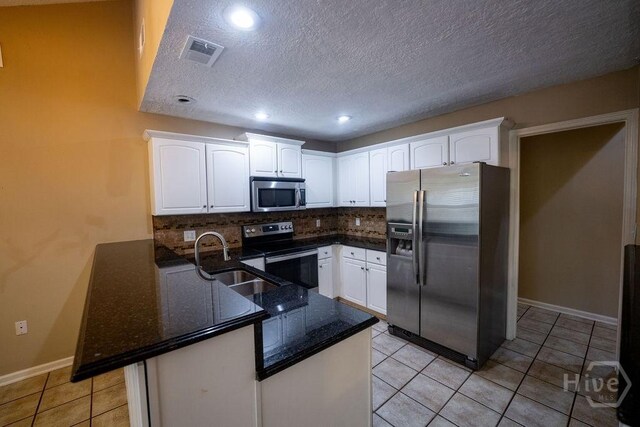 143 Village Lake Dr, Pooler, GA 31322 - kitchen featuring stainless steel appliances, a peninsula, white cabinets, backsplash, and a textured ceiling
