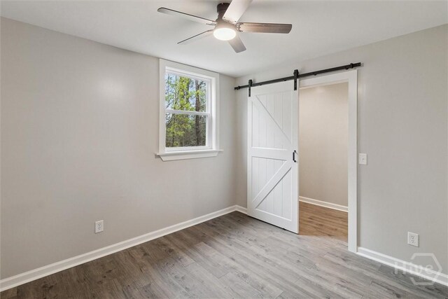 4342 Mud Rd, Brooklet, GA 30415 - unfurnished bedroom with wood finished floors, baseboards, a barn door, and a ceiling fan