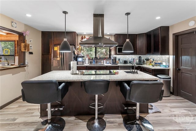 124 Denham Ln, Midway, GA 31320 - kitchen with island exhaust hood, stainless steel fridge with ice dispenser, dark brown cabinetry, light stone countertops, and decorative light fixtures