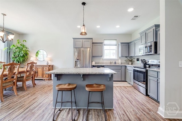 109 Amelia Ct, Guyton, GA 31312 - kitchen featuring stainless steel appliances, gray cabinetry, a kitchen island, light wood-style flooring, and a kitchen bar