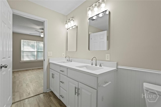 121 Warner Dr, Guyton, GA 31312 - full bathroom featuring wood finished floors, double vanity, a ceiling fan, toilet, and a wainscoted wall