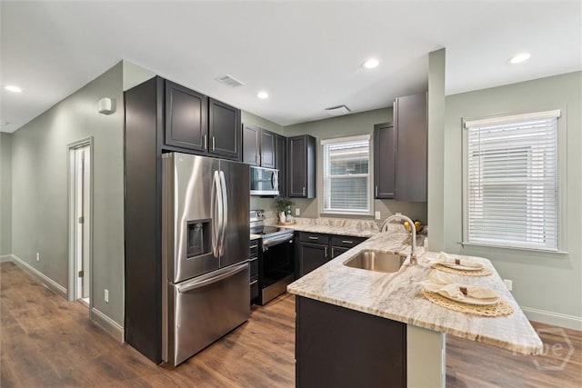 2142 New York Ave, Savannah, GA 31404 - kitchen featuring stainless steel appliances, a sink, a peninsula, light stone counters, and dark wood-style floors