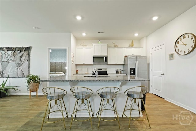116 Fremont Ln, Pooler, GA 31322 - kitchen with appliances with stainless steel finishes, a kitchen bar, dark stone counters, a center island with sink, and recessed lighting