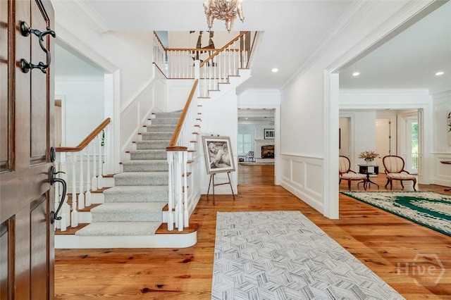 36 Belted Kingfisher Ln, Richmond Hill, GA 31324 - entrance foyer with wood finished floors, a decorative wall, ornamental molding, stairway, and a chandelier