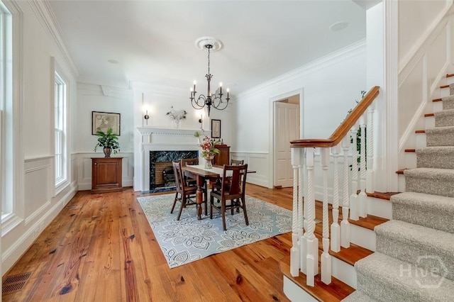 36 Belted Kingfisher Ln, Richmond Hill, GA 31324 - dining area featuring stairway, a decorative wall, crown molding, light wood-type flooring, and a chandelier