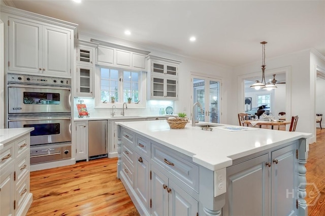 36 Belted Kingfisher Ln, Richmond Hill, GA 31324 - kitchen featuring double oven, a sink, light wood finished floors, light countertops, and crown molding