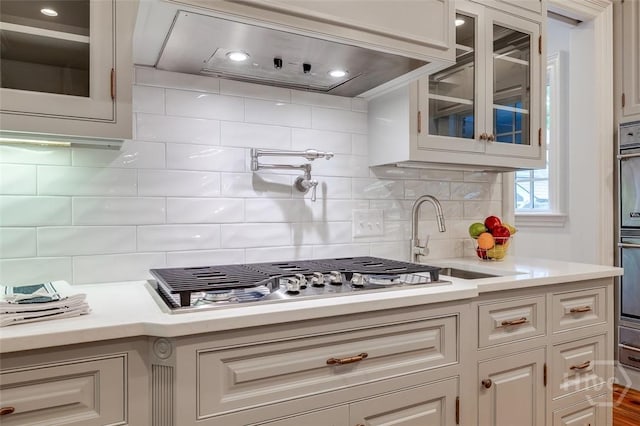36 Belted Kingfisher Ln, Richmond Hill, GA 31324 - kitchen with premium range hood, a sink, light countertops, stainless steel appliances, and glass insert cabinets