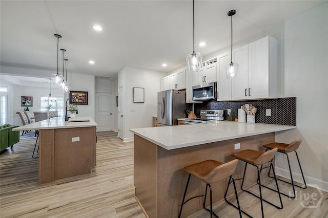 2 Iron Gate Ct, Pooler, GA 31322 - kitchen with stainless steel appliances, a sink, light wood-type flooring, a breakfast bar area, and backsplash