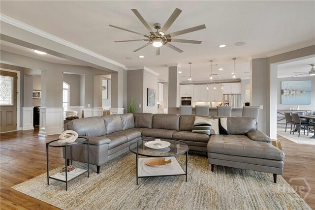907 Cheryl St, Savannah, GA 31410 - living room featuring a ceiling fan, light wood-type flooring, crown molding, a wainscoted wall, and a decorative wall