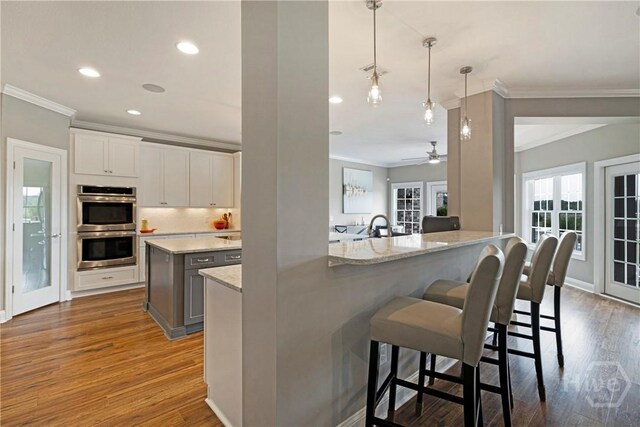907 Cheryl St, Savannah, GA 31410 - kitchen with crown molding, double oven, dark wood-style floors, a kitchen bar, and a ceiling fan