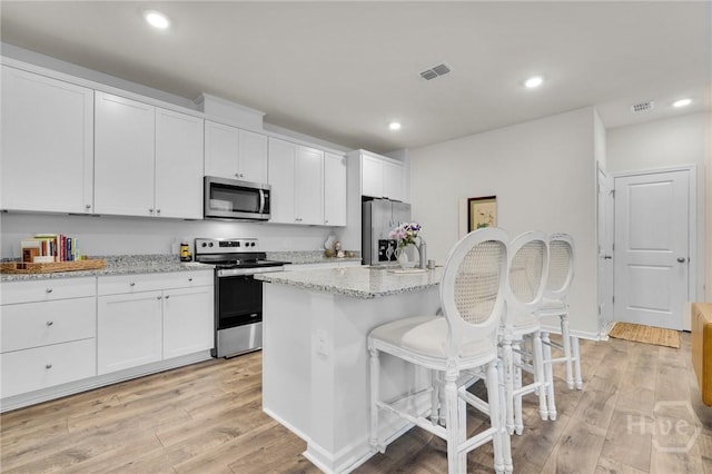 142 Benelli Dr, Pooler, GA 31322 - kitchen featuring appliances with stainless steel finishes, a kitchen breakfast bar, white cabinetry, a center island with sink, and recessed lighting