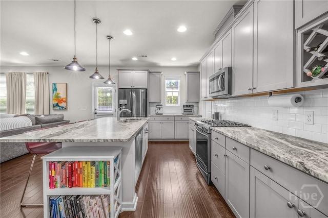 103 Safari Trl, Pooler, GA 31322 - kitchen with appliances with stainless steel finishes, decorative backsplash, a breakfast bar, light stone counters, and dark wood-type flooring