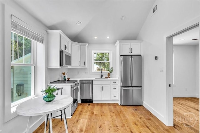 2136 Indiana Ave, Savannah, GA 31404 - kitchen featuring appliances with stainless steel finishes, white cabinetry, light wood finished floors, vaulted ceiling, and a sink
