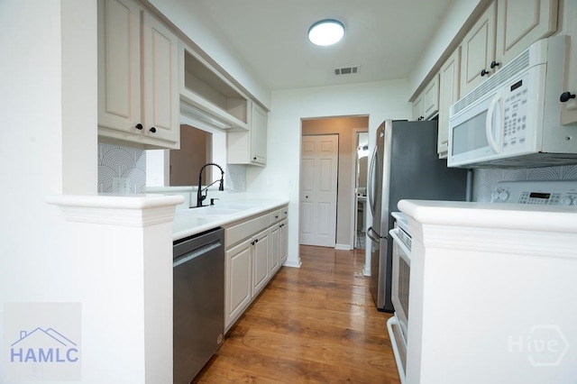 12300 Apache Ave Unit 604, Savannah, GA 31419 - kitchen with stainless steel appliances, a sink, light countertops, light wood finished floors, and backsplash