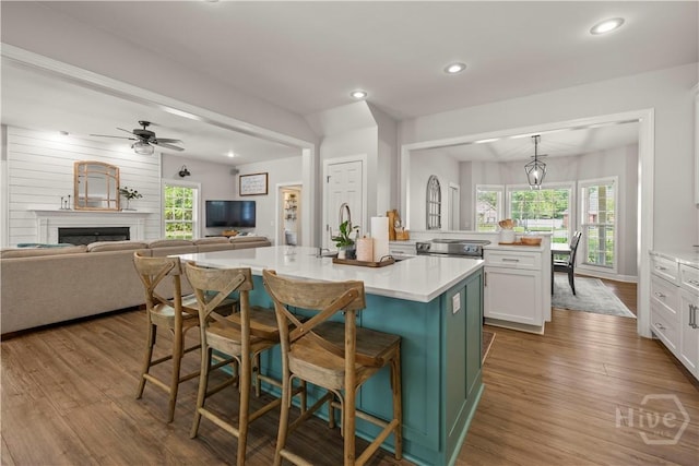 117 Myrtlewood Dr, Guyton, GA 31312 - kitchen with a kitchen island with sink, a breakfast bar area, wood finished floors, white cabinetry, and light countertops