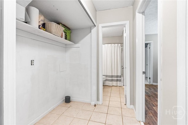 103 Mapmaker Cv, Savannah, GA 31410 - laundry area with light tile patterned flooring, baseboards, and a textured ceiling
