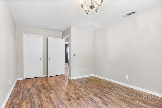 103 Mapmaker Cv, Savannah, GA 31410 - unfurnished bedroom with a chandelier, wood finished floors, baseboards, and a textured ceiling