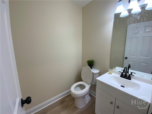 61 Port Dr, Richmond Hill, GA 31324 - bathroom with toilet, baseboards, wood finished floors, vanity, and a chandelier