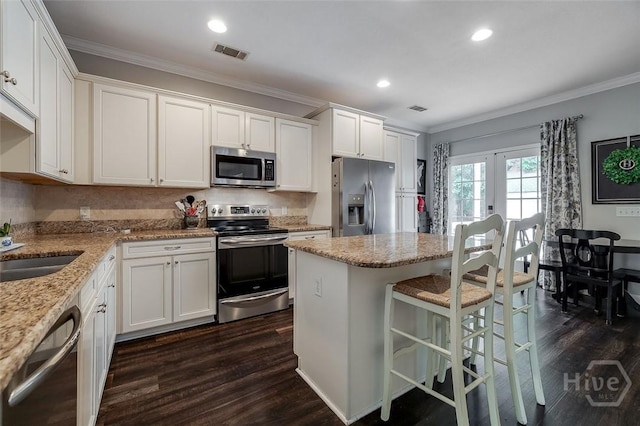 101 Sabal Ln, Savannah, GA 31405 - kitchen featuring appliances with stainless steel finishes, ornamental molding, dark wood-type flooring, white cabinetry, and recessed lighting