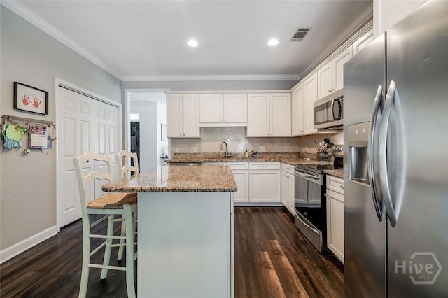 101 Sabal Ln, Savannah, GA 31405 - kitchen featuring stainless steel appliances, crown molding, dark wood finished floors, a center island, and light stone countertops