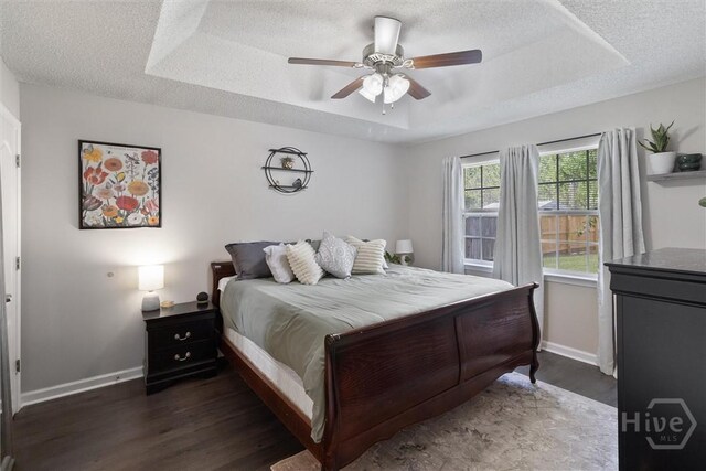 2000 Ossabaw Dr, Hinesville, GA 31313 - bedroom with a raised ceiling, dark wood-style flooring, baseboards, a textured ceiling, and ceiling fan