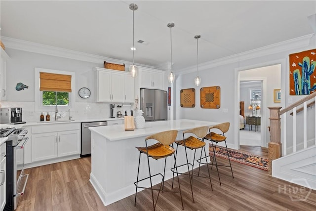 117 Quince St, Pooler, GA 31322 - kitchen featuring appliances with stainless steel finishes, a sink, a breakfast bar area, light wood finished floors, and a kitchen island