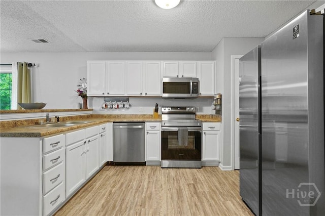 21 Hawser Way, Port Wentworth, GA 31407 - kitchen featuring appliances with stainless steel finishes, a textured ceiling, a sink, light wood-style flooring, and white cabinetry