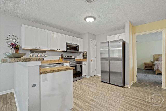 21 Hawser Way, Port Wentworth, GA 31407 - kitchen with stainless steel appliances, a peninsula, white cabinets, light wood-type flooring, and a textured ceiling