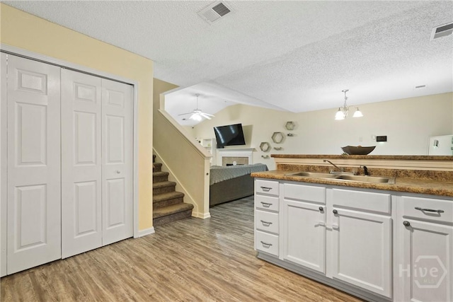 21 Hawser Way, Port Wentworth, GA 31407 - kitchen with a sink, a fireplace, light wood-style flooring, a textured ceiling, and white cabinets