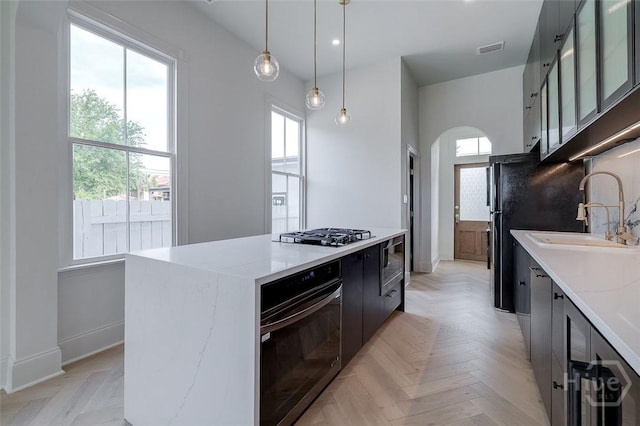 316 W 38th St, Savannah, GA 31401 - kitchen with black oven, arched walkways, a sink, modern cabinets, and stainless steel gas stovetop