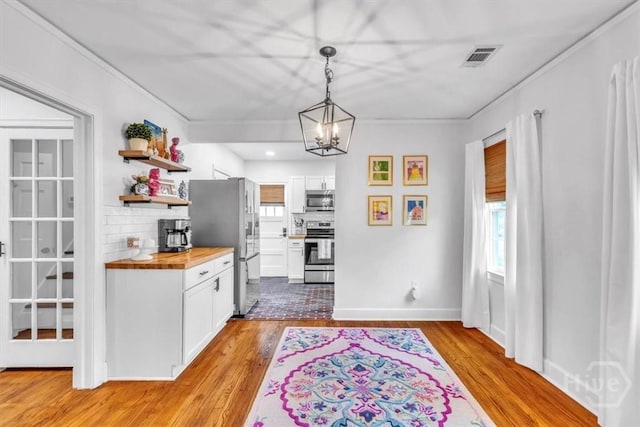 2117 E 42nd St, Savannah, GA 31404 - kitchen with butcher block counters, stainless steel appliances, open shelves, healthy amount of natural light, and ornamental molding